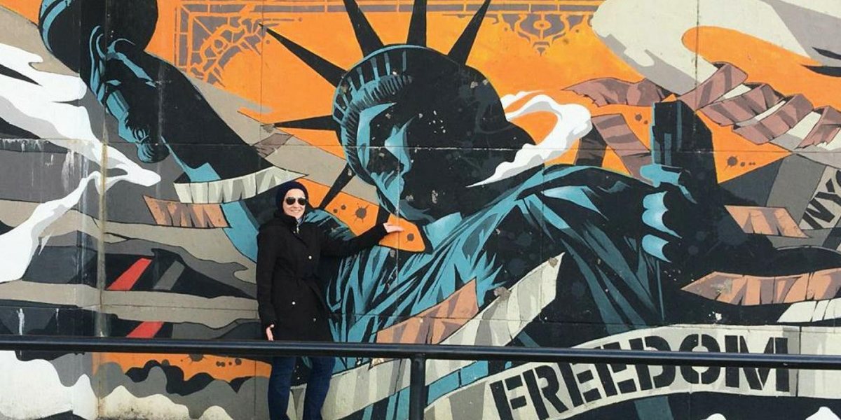 Dr. Salma Waly in front of a Statue of Liberty mural reading Freedom in New York City