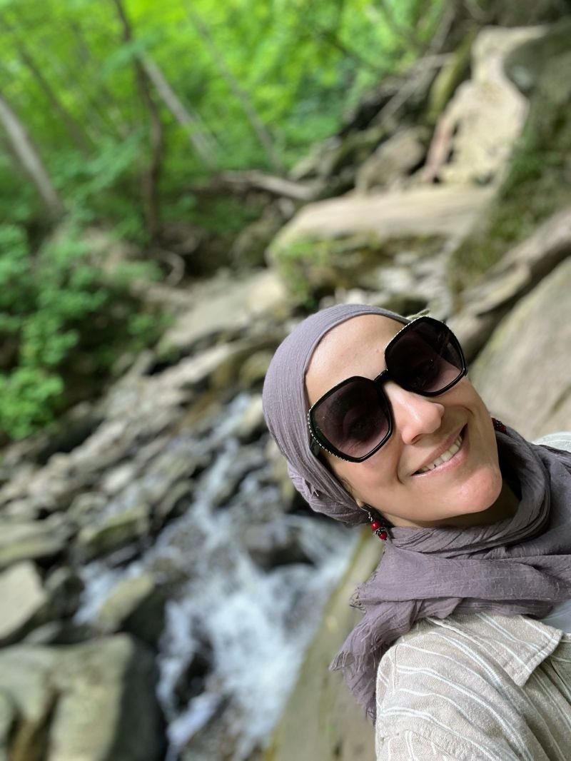 Dr. Salma Waly smiling on a hike beside a waterfall